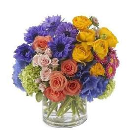 Bright mixed bouquet of blue daisies and peach and yellow roses in a clear glass cylinder vase