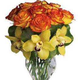 Arrangement of orange roses and yellow orchids in a clear glass vase