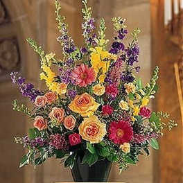 Tall multicolor pedestal arrangement with yellow, pink, and purple flowers in a black urn-style vase.