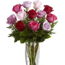 Tall clear glass vase of red, pink, and lavender roses
