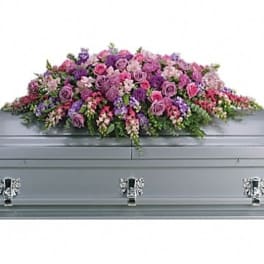 Pink and purple floral casket spray on a gray casket