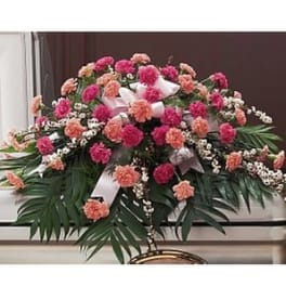 Pink and peach floral casket spray with white ribbons