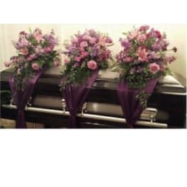 Three pink and purple floral sprays on a casket