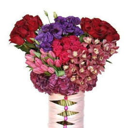 Tall pink and red mixed flower arrangement in a ribbon-wrapped glass vase with gemstone accents