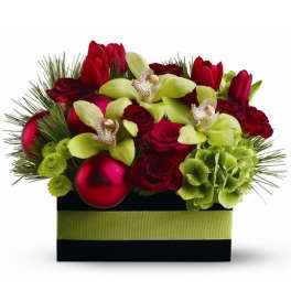 Low rectangular arrangement of red roses and tulips with green orchids, hydrangea, pine and red ornaments.