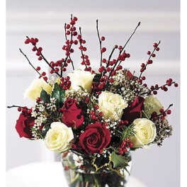 Arrangement of red and white roses with red berries and filler flowers in a clear glass vase
