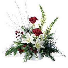 Low centerpiece with red roses and white lilies in a white container with decorative white branches