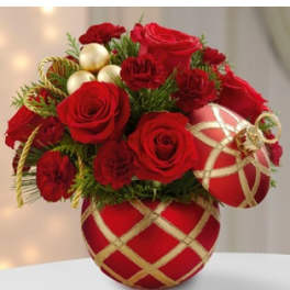 Red roses and carnations arranged in a red ornament-shaped container with gold accents and baubles.