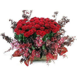 Large arrangement of red roses with pink orchids and red accents in a low gold bowl