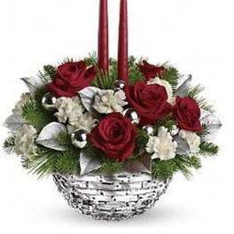 Red and white floral centerpiece with evergreens, silver accents, and two tall red candles in a white basket