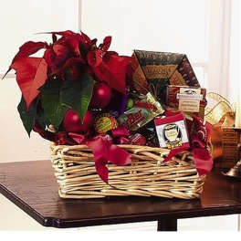 Wicker gift basket with red poinsettia plant, red ornaments, and assorted packaged snacks and treats