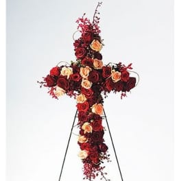 Tall standing cross of red and peach roses on a metal easel