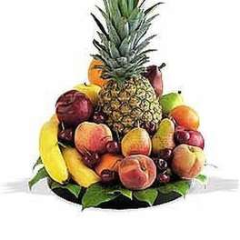 Assorted fresh fruits arranged around a tall pineapple on a platter