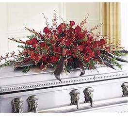Red casket spray with roses and trailing blooms on a silver casket