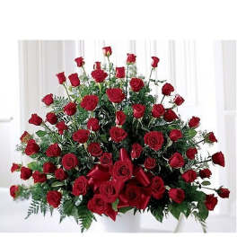 Large fan-shaped arrangement of red roses in a white container with a red ribbon bow