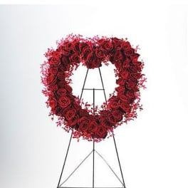 Heart-shaped wreath of red roses on a tall black metal easel