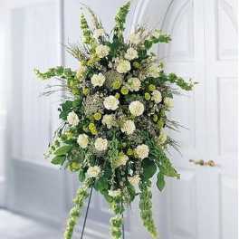Tall standing spray of white and green flowers on an easel in a bright room