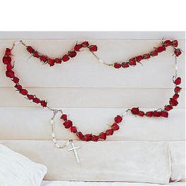 Wall-hung garland of red rose buds shaped like a rosary with white beads and cross