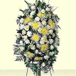 Tall standing spray of white and yellow flowers with greenery on a metal easel