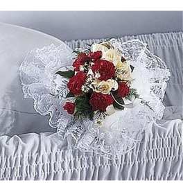 Red and cream flower pillow with lace resting on a white casket interior
