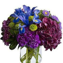 Compact purple and blue mixed flower arrangement in a clear glass cylinder vase