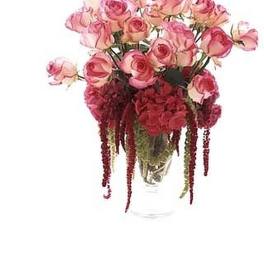 Tall arrangement of pink roses with dark red blooms and trailing accents in a clear glass vase