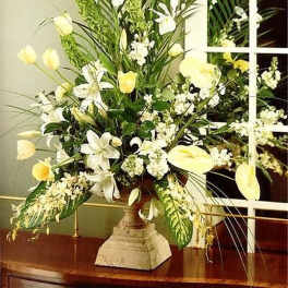 Tall arrangement of white and pale yellow flowers in a stone urn vase