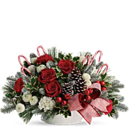 Christmas bouquet with red roses, white flowers, candy canes, and pinecones in a white container