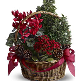 Basket arrangement with red flowers, greenery, pinecones, and red ribbon