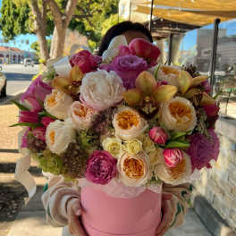 Large bouquet of pink, white, and peach flowers in a pink hat box