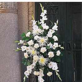 Standing spray of white gladiolus, carnations, and spider mums on an easel.