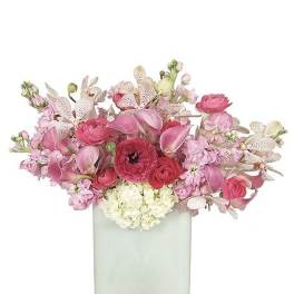 Low arrangement of pink flowers with orchids, calla lilies, and hydrangea in a frosted white cube vase