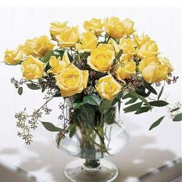Arrangement of yellow roses with filler in a clear pedestal glass vase