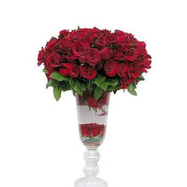 Tall clear glass vase filled with clustered red roses and submerged blooms in water
