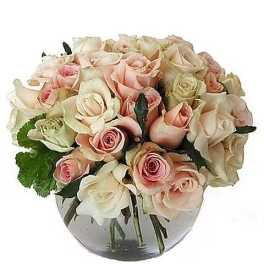 Low round arrangement of blush and cream roses in a clear glass bowl vase