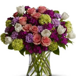 Mixed bouquet of pink roses, white tulips and purple flowers in a clear glass vase