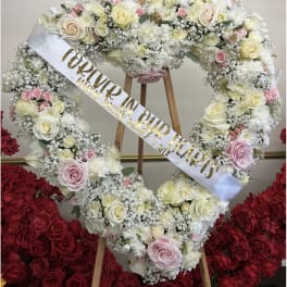 Heart-shaped floral wreath with white and pink roses on an easel