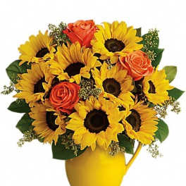 Sunflowers and orange roses arranged in a yellow pitcher vase