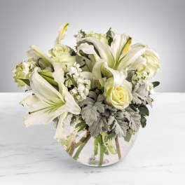White lilies and roses arranged in a clear glass vase