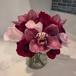 Bouquet of red roses and pink orchids in a glass vase
