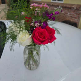 Bouquet of red and white roses in a clear glass jar vase
