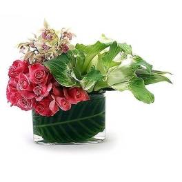 Low rectangular vase with pink roses, green and white calla lilies, and orchids arranged asymmetrically