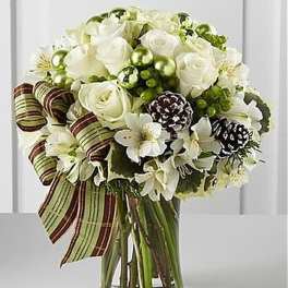 Bouquet of white roses and lilies with pinecones and green ornaments in a clear glass vase