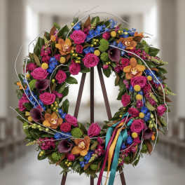 Colorful floral wreath with roses, orchids, and ribbons on an easel