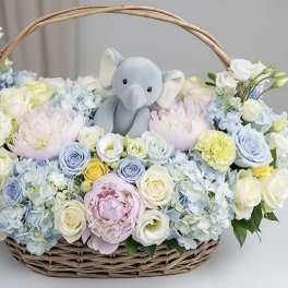 Basket of pastel flowers with a plush elephant in the center