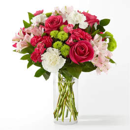 Bouquet of pink roses, carnations, and white flowers in a clear glass vase
