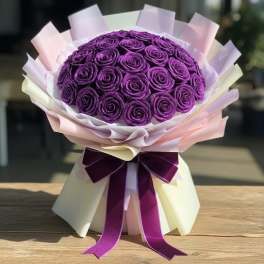 Purple rose bouquet wrapped in pastel paper with a ribbon