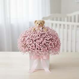 Pink baby's breath arrangement with a teddy bear topper in a white box