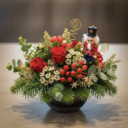 Holiday arrangement with red roses and a nutcracker figurine in a black bowl