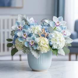 Blue and white floral arrangement in a light blue vase with a small rocking horse ornament